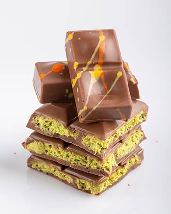 milk chocolate bar filled with pistachio cream and splashed with orange and yellow decoration
