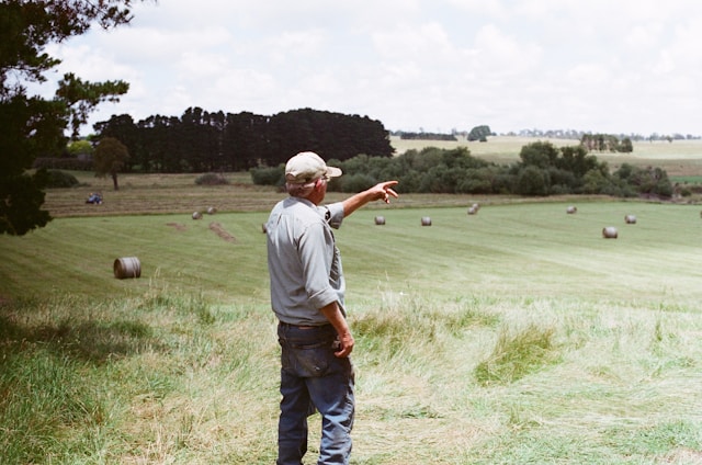 image of farmer pointing into feild with round hay bales