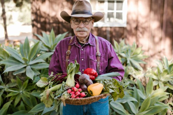 A older farmer carrying a plate of veggies.